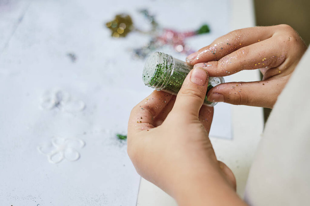 The childs hands holding the jar with green sparkles for creating art work - Fotoğraf, Görsel