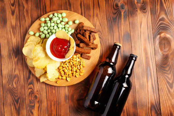 Beer in a bottle with dry salty snack, on a wooden table with free space. - Foto, immagini