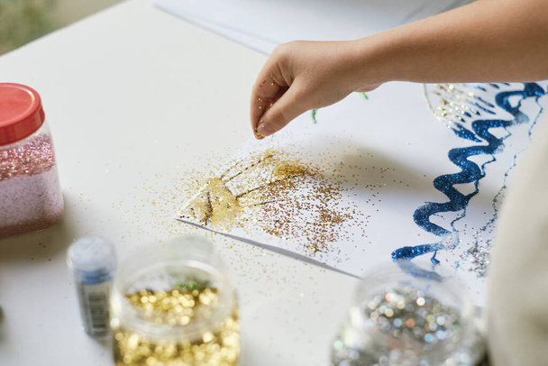 Childs hand using fingers for pouring sparkles for create a picture - 写真・画像
