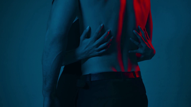 žena dotýká záda svalnatého muže na modré - Záběry, video