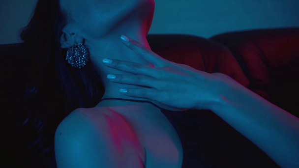 seductive woman touching neck and sitting on blue with smoke - Video, Çekim