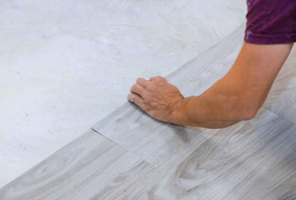 Work on laying worker installing new vinyl tile laminate wood texture floor. - Фото, зображення