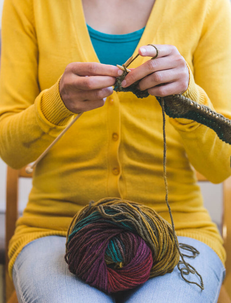 女性の手を閉じる。若い女性が編み物をしている。針と糸を編む。多色糸。ナイターの手だ。趣味だ。針仕事への情熱. - 写真・画像