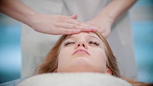Massaggio massaggiatrice sta impastando i suoi clienti faccia con i palmi delle mani
 - Foto, immagini
