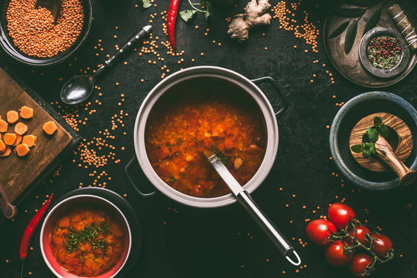 Healthy vegan lentil soup in cooking pot with ladle on dark kitchen table background with ingredients. Vegetarian food. Clean diet eating. Source of plant based protein - Foto, immagini