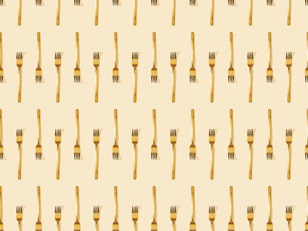 top view of golden forks isolated on beige, seamless background pattern - 写真・画像