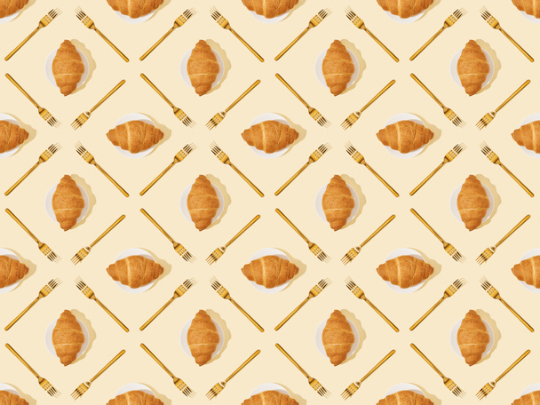 top view of golden forks and croissants on beige, seamless background pattern - Fotoğraf, Görsel
