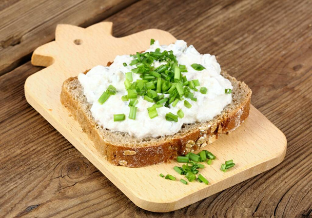 Συκώτι πατέ πάνω από καφέ ψωμί με φρέσκο πράσινο κρεμμύδι. Σπιτική εξάπλωση από συκώτι γάδου, τυρί cottage και κομμένες πίκλες σε ξύλο κοπής. - Φωτογραφία, εικόνα