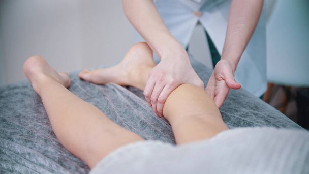 Μασάζ - μασάζ θεραπευτής ζυμώνει τα πόδια μιας νεαρής γυναίκας - Φωτογραφία, εικόνα