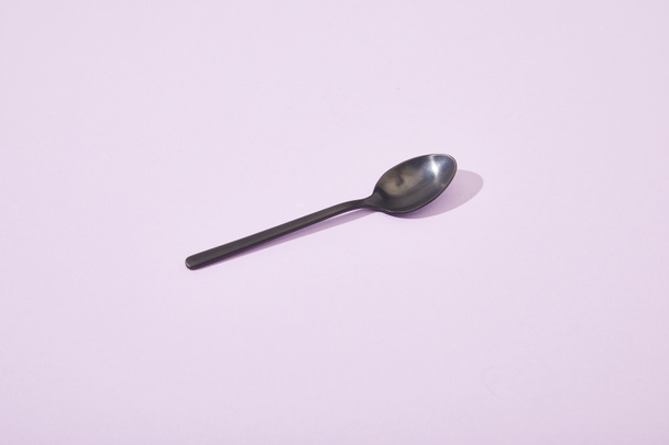 metal shiny black spoon on violet background - Valokuva, kuva