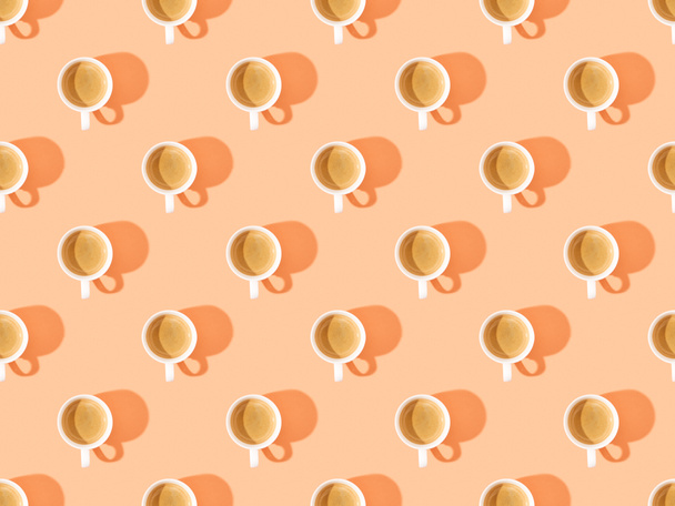top view of cups of fresh coffee on orange, seamless background pattern - Фото, изображение