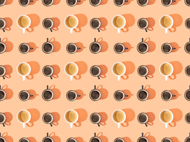 bovenaanzicht van kopjes verse koffie op oranje, naadloze achtergrond patroon - Foto, afbeelding