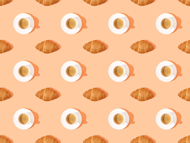 top view of fresh croissants on plates and coffee on orange, seamless background pattern - Фото, изображение