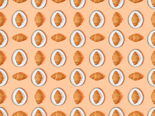 top view of fresh croissants on plates on orange, seamless background pattern - Foto, Imagen