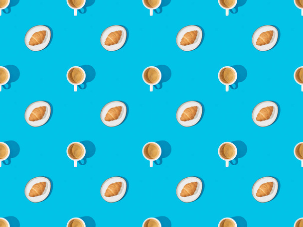 top view of croissants on plates and coffee on blue, seamless background pattern - Zdjęcie, obraz