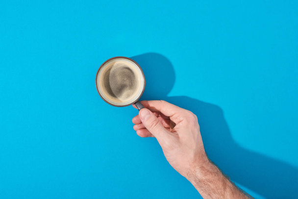 cropped view of man holding cup of fresh coffee on blue background - Photo, Image