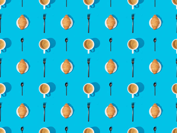 top view of cutlery, croissants on plates and coffee on blue, seamless background pattern - Photo, Image