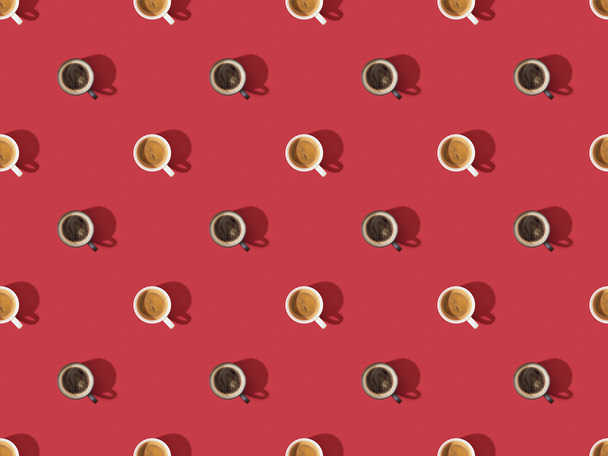Bovenaanzicht van kopjes verse koffie op rode, naadloze achtergrond patroon - Foto, afbeelding