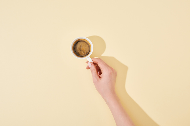 cropped view of woman holding cup of fresh coffee on beige background - Photo, Image
