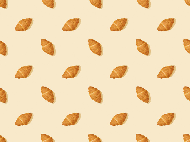 top view of fresh croissants on beige, seamless background pattern - Фото, изображение