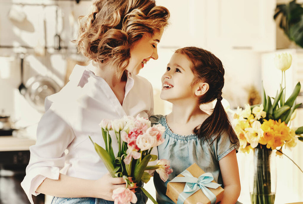 Счастливого Дня Матери! ребенок дочь поздравляет мать с праздником и дарит цветы
 - Фото, изображение