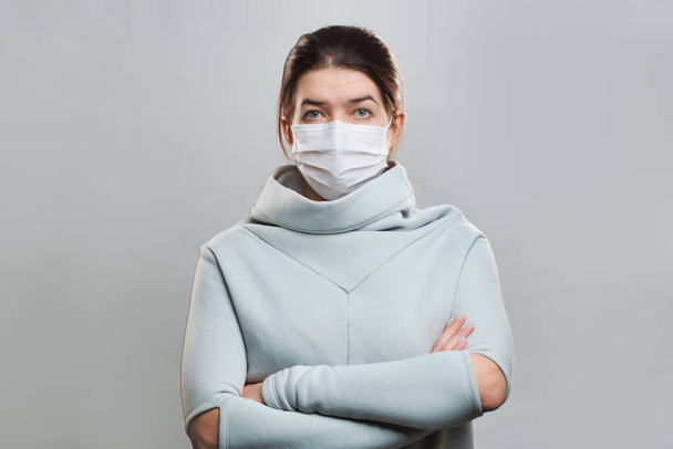 Young woman in medical mask with arms crossed isolated in studio - 写真・画像