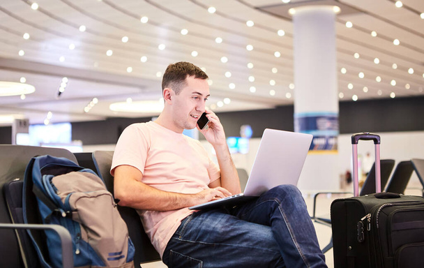 Homem de negócios viajante europeu (passageiro) com um smartphone e laptop na mão está esperando pela partida (voo) no Aeroporto Internacional de Istambul Havalimani (IST Airport
) - Foto, Imagem