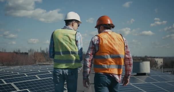 Inżynier i technik omawiający między panelami słonecznymi - Materiał filmowy, wideo