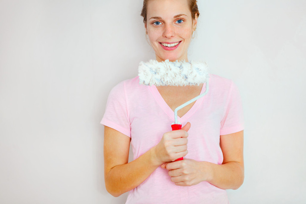 Happy Woman standing againtst wall with roller brush. - Photo, image