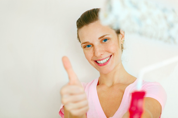 Happy Woman showing thumb up with roller brush. - Foto, imagen