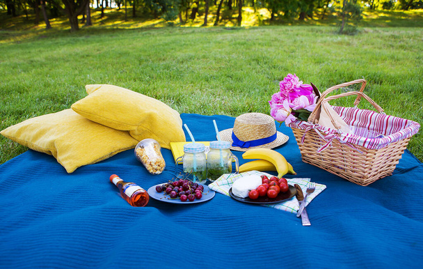 Picnic at the park on the grass: tablecloth, basket, healthy food and accessories, top view - Photo, image