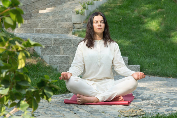 Nuori nainen istuu meditoi raitista ilmaa luonnonpuistossa
. - Valokuva, kuva