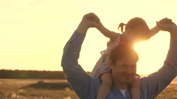 Папа с любимой дочерью на плечах танцует в полете и смеется. Счастливый ребенок играет со своим отцом на закатном поле. Силуэт мужчины и ребенка. Концепция семьи и детства
 - Кадры, видео