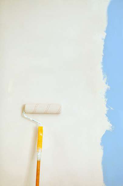 Roller brush with orange grip against wall. - Photo, Image