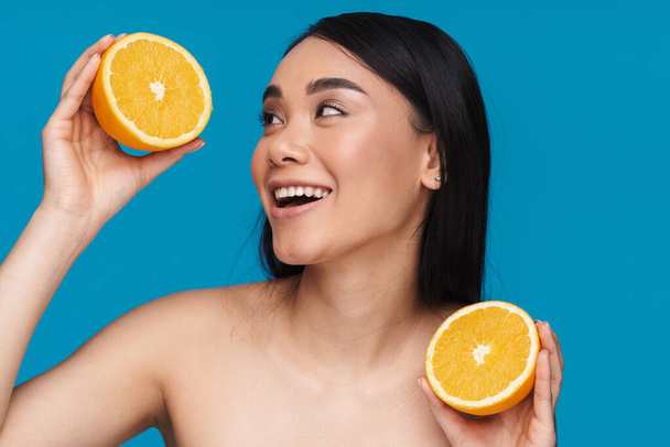 Foto einer fröhlichen asiatischen jungen Frau posiert isoliert über blauer Wand Hintergrund mit orange. - Foto, Bild