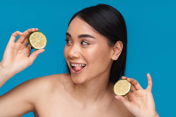 Photo of happy optimistic pretty young woman posing isolated over blue wall background with lime. - Foto, Imagen