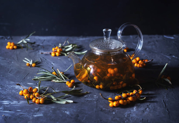 sea buckthorn tea in a glass teapot on the wood background - Foto, Imagen