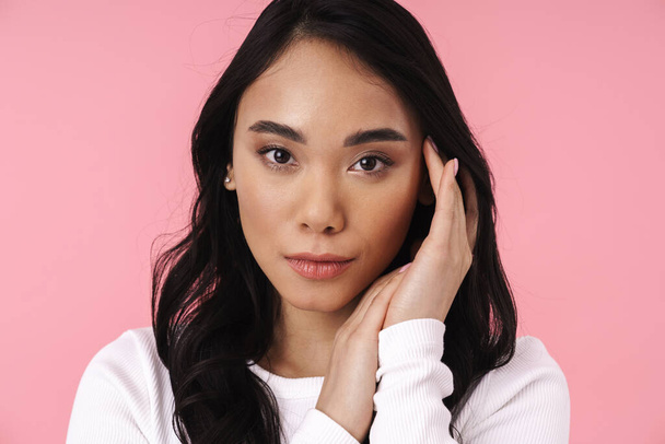 Image of young brunette asian woman in casual clothes looking at camera isolated over pink background - Fotografie, Obrázek