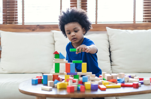 Happy African American cute little boy bawić się drewnianymi klockami budowy na stole w domu. Nauka kreatywnej koncepcji - Zdjęcie, obraz