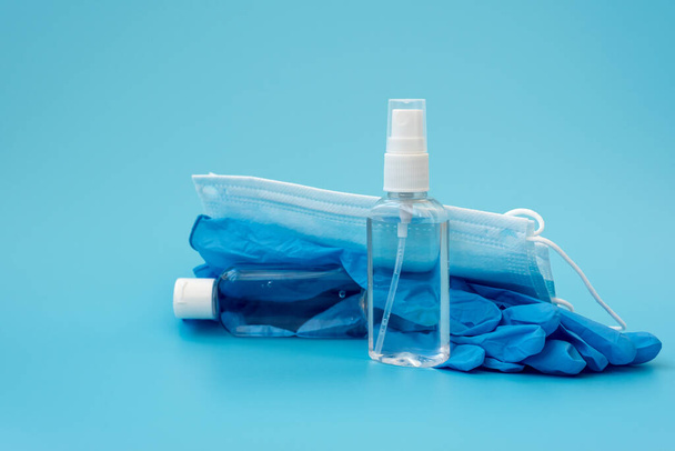Set of antiseptic items. Wearing mask, medical gloves, bottles of antiseptic hand gel and spray on blue background. Flu, illness, pandemic concept - Photo, image