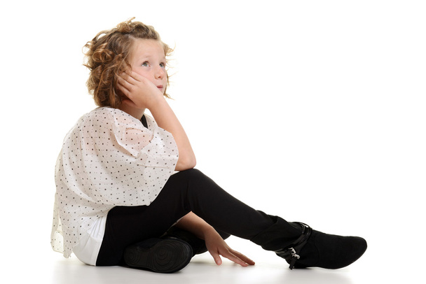 Little girl wearing white top and black pants sitting - Foto, Imagen