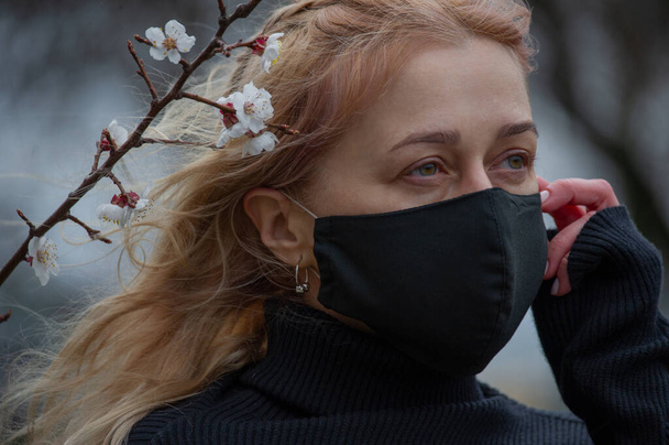 医療面のマスクを路上で春の服を着た美しい若い女性。人工呼吸器で30歳の女性の閉鎖は、コロナウイルスとの感染から保護するために- Covid19.コロナウイルス - 写真・画像