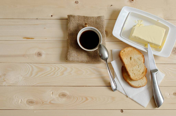 varhain aamulla kupin kahvia ja leivänpaahtimet voita. virkistävä aamiainen. puinen pöytä taustana
 - Valokuva, kuva
