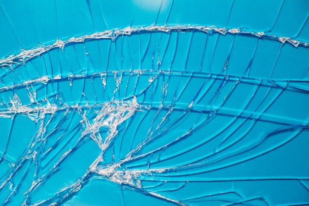Fondo azul a través del cristal roto de la ventana
. - Foto, Imagen