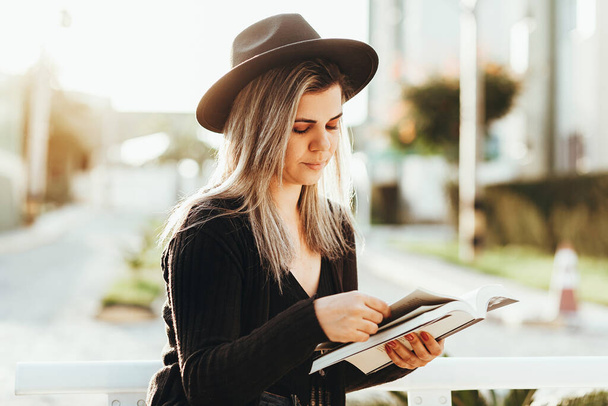 Retrato de mujer elegante con sombrero fedora libro de lectura al aire libre
 - Foto, Imagen