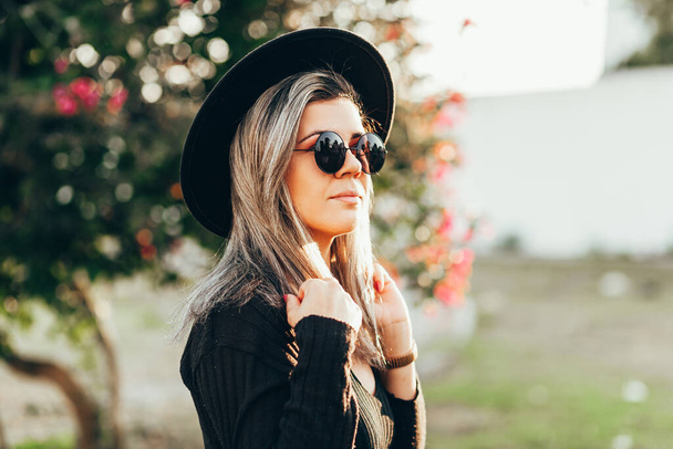 Portrait of elegant woman wearing fedora hat and sunglasses outdoors - Фото, зображення