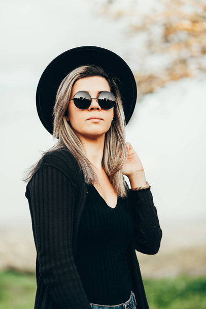 Portrait of elegant woman wearing fedora hat and sunglasses outdoors - Fotoğraf, Görsel