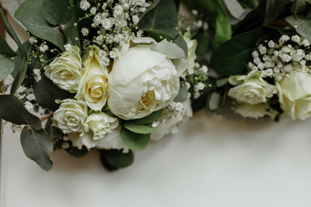 wedding bouquets of white roses and greens for bridesmaids on a white table. brides morning. wedding accessories. selective focus. - Фото, изображение