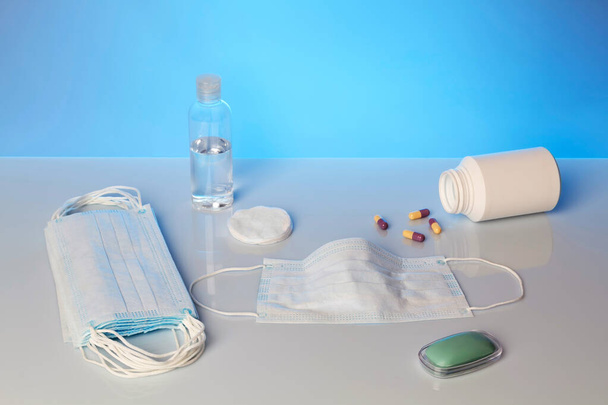 Vorbeugung gegen die Epidemie von Viruserkrankungen. Ein Stück Seife, Alkohol und eine medizinische Maske auf blauem Hintergrund - Foto, Bild