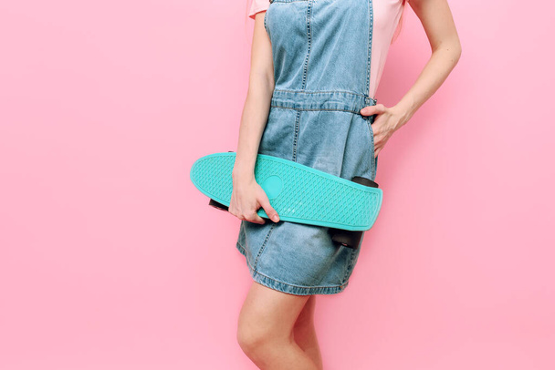 Close- up of a girl holding a skateboard on an isolated pink background - Foto, immagini
